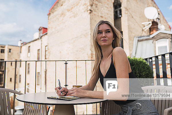 Porträt einer jungen Frau  die auf dem Balkon sitzt und Notizen macht