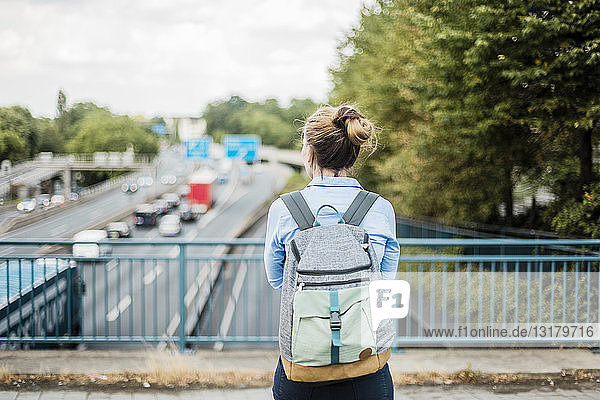 Rückansicht einer Frau mit Rucksack auf der Autobahnbrücke