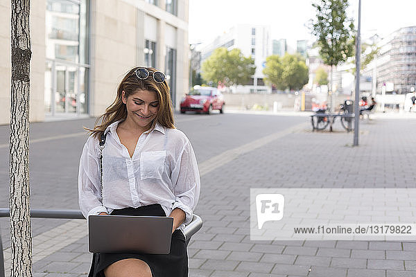 Smiling businesswoman using laptop outdoors