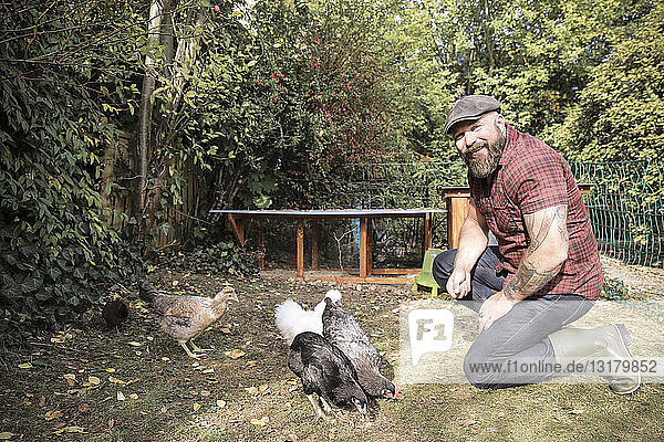 Mann im eigenen Garten  Mann beim Füttern von Freilandhühnern