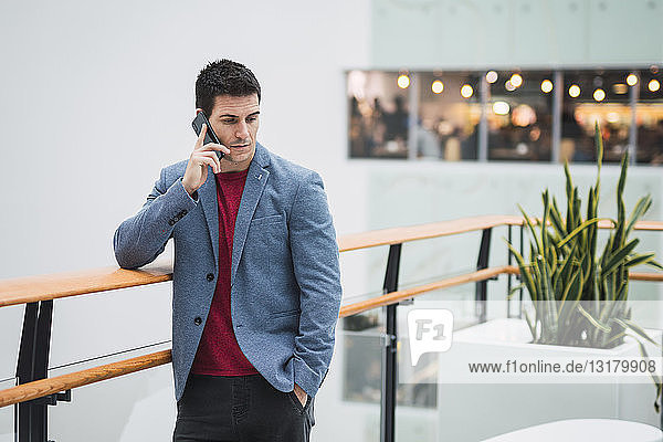 Geschäftsmann in der Lobby eines modernen Gebäudes  mit Smartphone