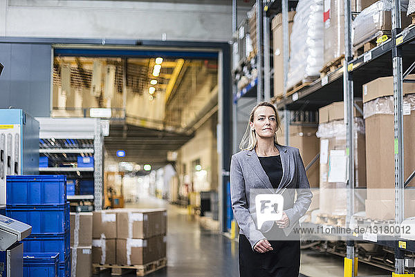 Porträt einer selbstbewussten Frau mit Tablette im Fabriklager