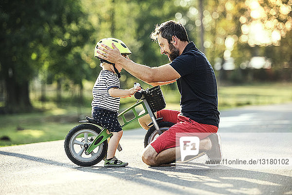 Vater unterstützt kleinen Sohn auf dem Fahrrad
