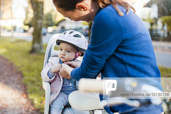 Mutter und Tochter fahren Fahrrad, das Baby trägt einen Helm und