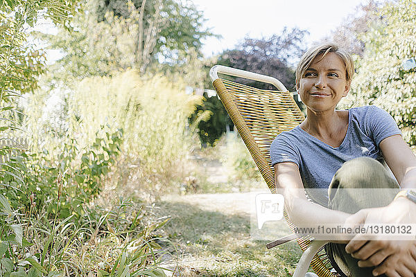 Frau sitzt im Garten auf einem Stuhl