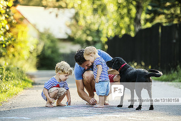 Reifer Mann spielt im Sommer mit seinen kleinen Kindern auf der Straße
