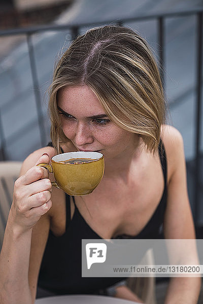 Junge Frau trinkt eine Tasse Kaffee auf der Dachterrasse