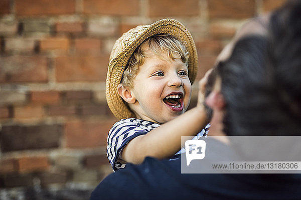 Porträt eines lachenden Kleinkindes,  das sich mit seinem Vater amüsiert