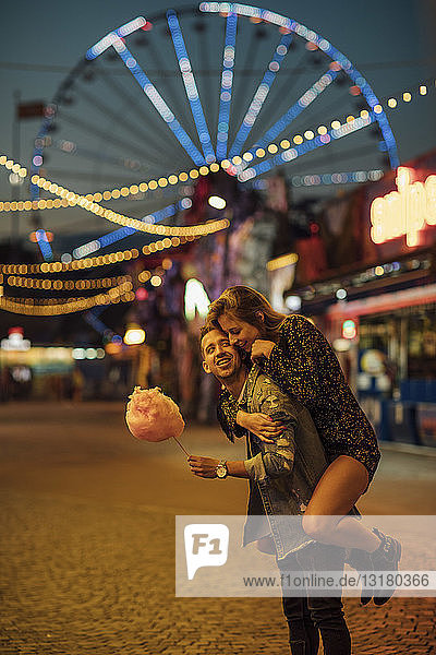Young couple having fun at a funfair  eating candyfloss