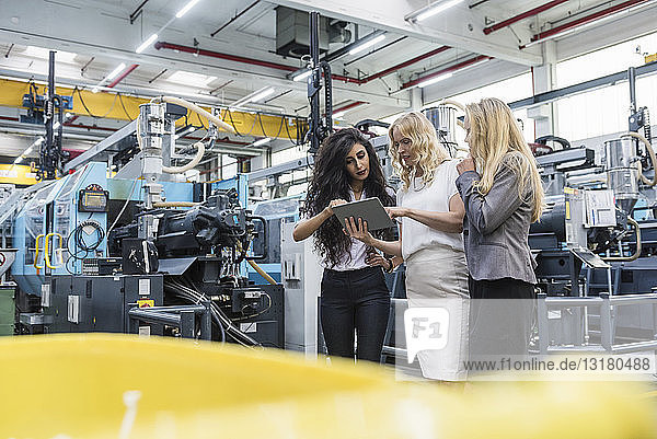 Three women with tablet talking in factory shop floor