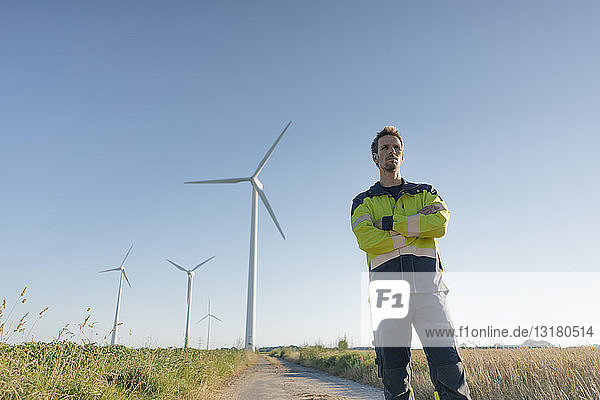 Ingenieur  der auf einem Feldweg bei einem Windpark steht