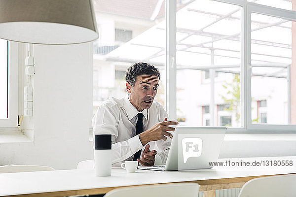 Shocked businessman looking at laptop on table in office