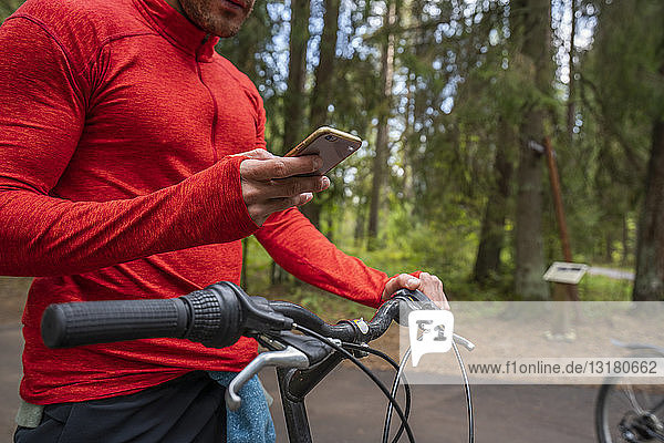 Mountainbiker mit Smartphone in einem Wald