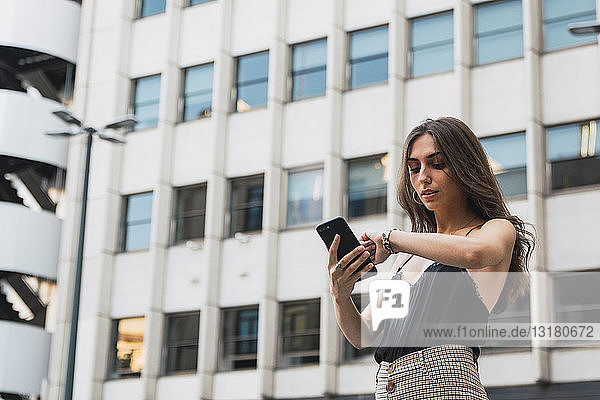 Portrait of young woman with cell phone checking the time