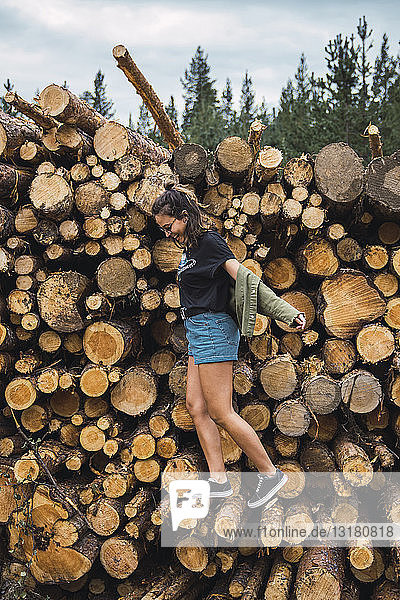 Glückliche junge Frau balanciert auf einem Holzstapel