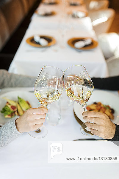 Close-up of couple clinking wine glasses in a restaurant