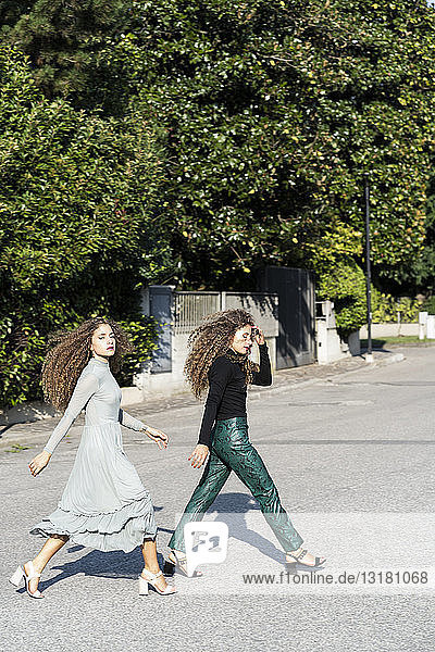 Modische Zwillingsschwestern überqueren die Straße