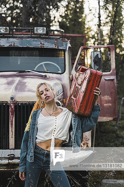 Young woman posing at a broken vintage truck  holding petrol can