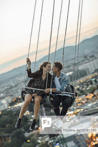Verliebtes junges Paar reitet Kettenkarussell auf einem Rummelplatz