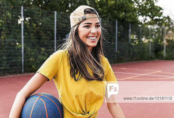 Happy young woman playing basketball