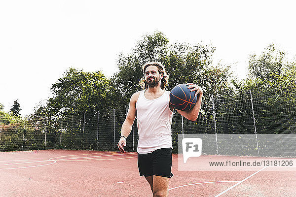 Junger Mann verlässt den Basketballplatz mit einem Ball