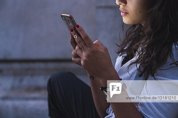 Young woman using cell phone at twilight  partial view