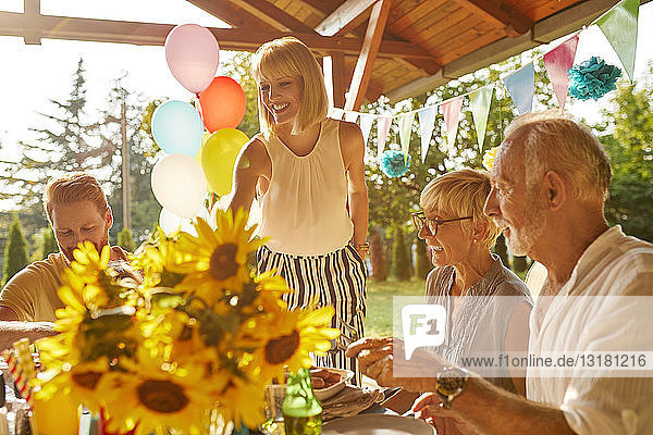Glückliches Paar  dessen Eltern ein Gartenfest feiern