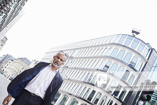 Großbritannien  London  Porträt eines grauhaarigen Senior-Geschäftsmannes  der im Finanzdistrikt spazieren geht