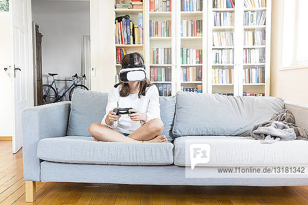 Mädchen sitzt zu Hause auf der Couch und benutzt eine Virtual-Reality-Brille