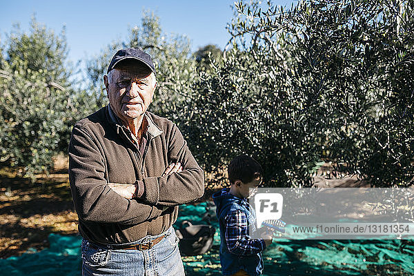 Porträt eines älteren Mannes mit seinem Enkel im Olivenhain