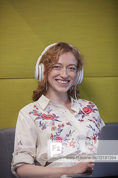 Junge Frau  die in einem modernen Kreativbüro arbeitet und Kopfhörer trägt