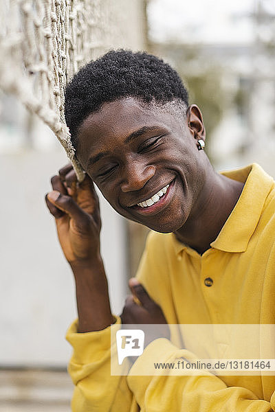 Porträt eines jungen schwarzen Mannes am Volleyballnetz stehend  lachend