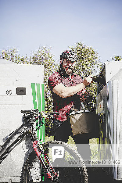 Porträt eines Mannes  der Glasflaschen in Flaschen recycelt Radfahrer