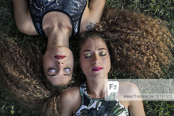 Porträt der Zwillingsschwestern in Rouge auf einer Wiese liegend  Draufsicht
