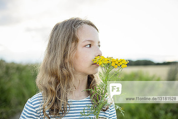 Girl in nature smelling at a wild flower