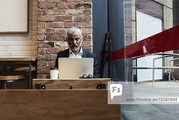 Senior businessman working on laptop in a coffee shop