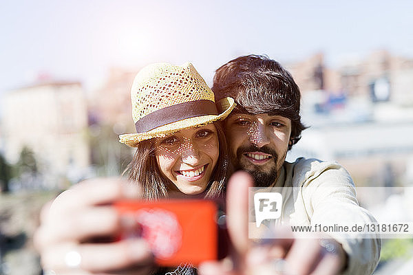 Porträt eines glücklichen jungen Paares  das sich mit einem Smartphone selbstständig macht