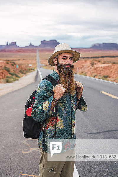 USA  Utah  Mann mit Rucksack steht auf der Straße zum Monument Valley