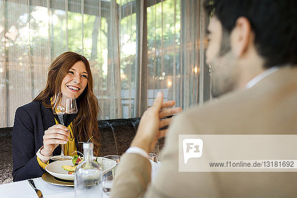Smiling woman with glass of red wine looking at man in a restaurant