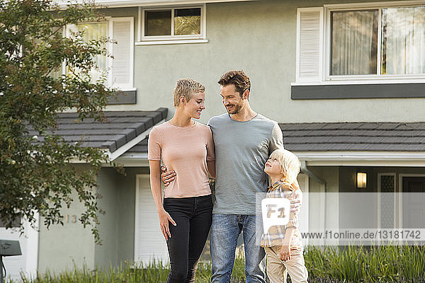 Lächelnde Eltern mit einem vor ihrem Haus stehenden Jungen