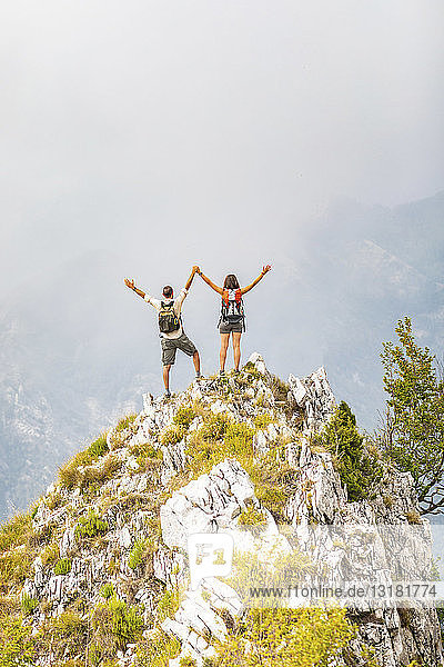 Italy  Massa  happy couple cheering on top of a peak in the Alpi Apuane mountains