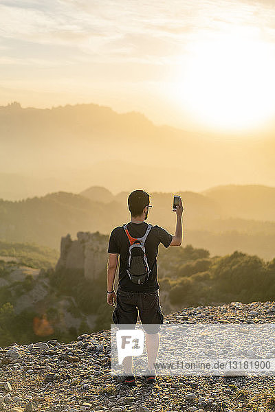 Spain  Barcelona  Natural Park of Sant Llorenc  man hiking and taking a picture of the view at sunset