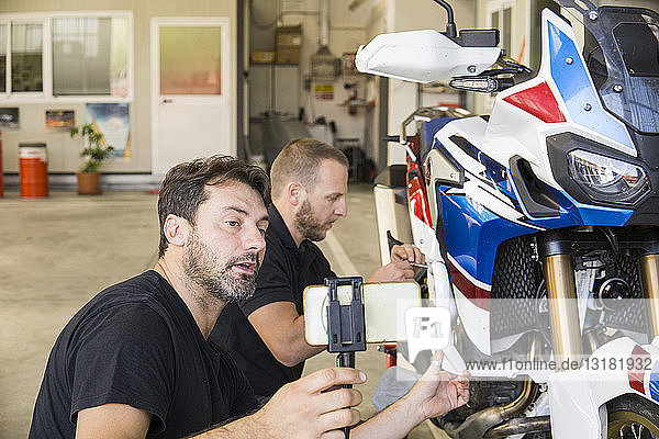 Von seinem Partner gefilmter Mechaniker bei der Arbeit am Motorrad in der Werkstatt