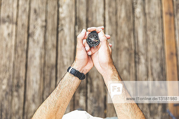 Close-up of man on boardwalk holding a compass