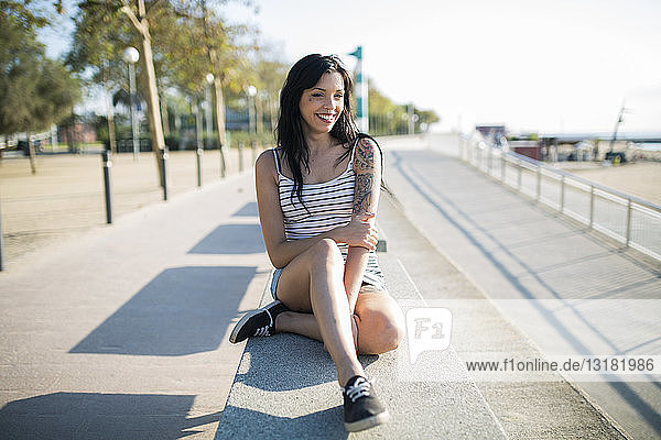 Lächelnde tätowierte junge Frau entspannt auf Bank