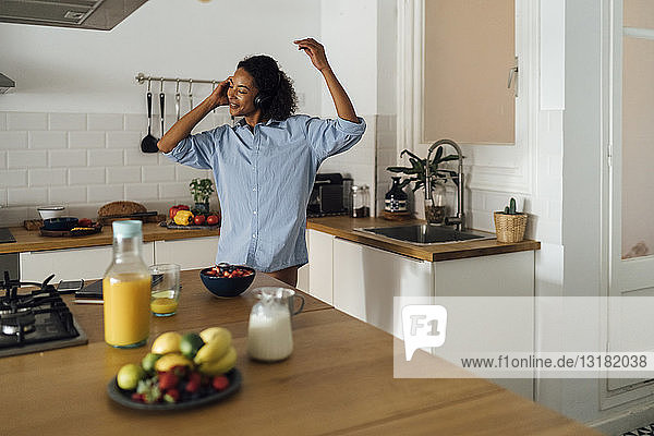 Frau  die morgens in ihrer Küche tanzt und Musik hört