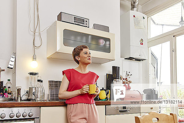 Lächelnde Frau bei einer Kaffeepause in der Küche