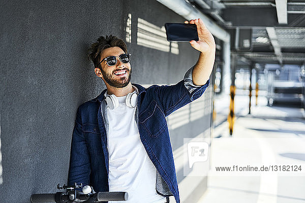 Porträt eines lächelnden Mannes  der sich mit einem Smartphone selbstständig macht