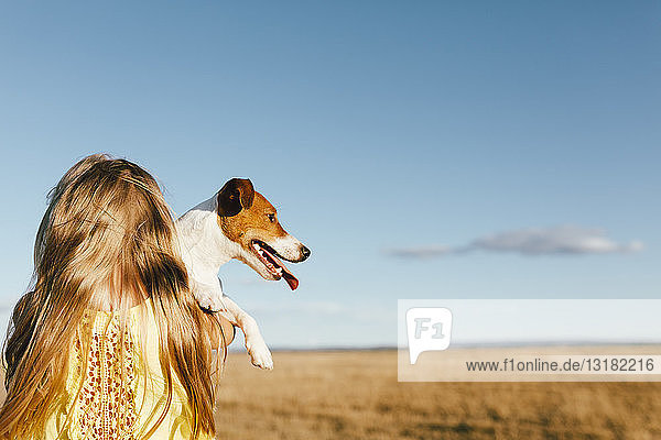 Mädchen hält Hund auf einem Feld