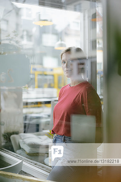 Portrait of young woman leaning against French door in a cafe